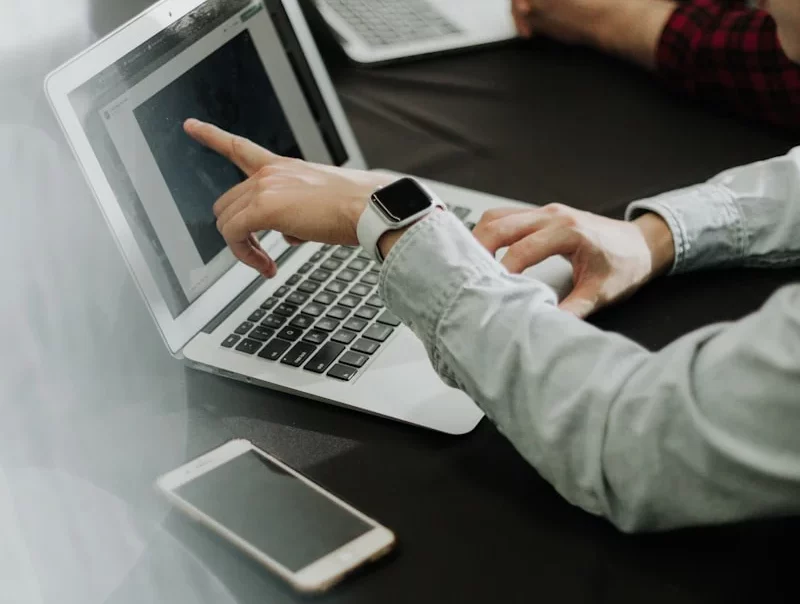 two people sitting at a table with laptops